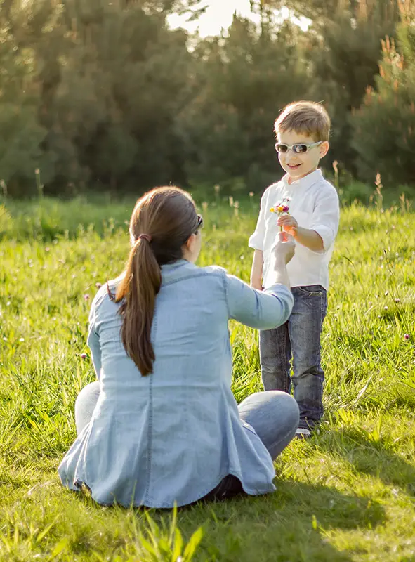 Son giving a bouquet of flowers to his mother in a field